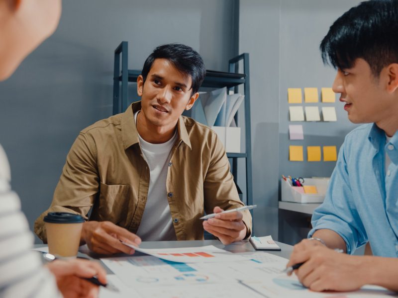 Happy young Asia businessmen and businesswomen meeting brainstorming some new ideas about project to his partner working together planning success strategy enjoy teamwork in small modern home office.
